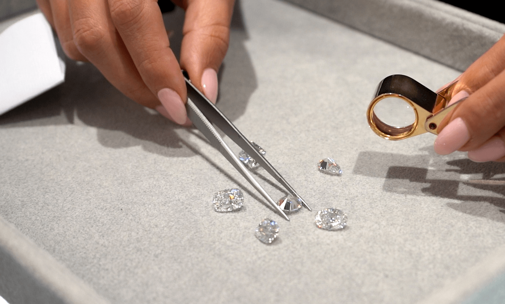A gemologist hand-selecting diamonds with tweezers and a jeweler's loupe